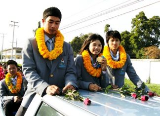 Noppakao Poonpat, flanked by fellow student teammates from the 2010 Asian Games, shows off her sailing gold medal in an open topped parade around Sattahip, Monday, November 29.